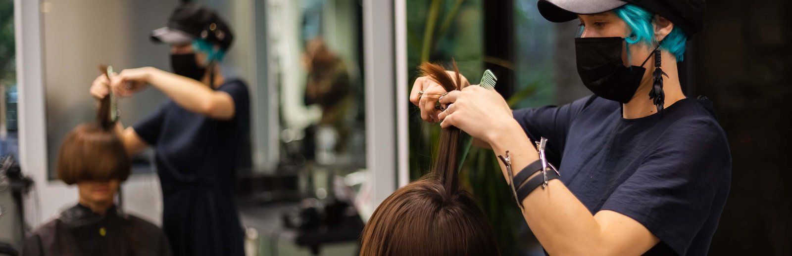 A professional girl hairdresser makes a client haircut. The girl is sitting in a mask in beauty the salon