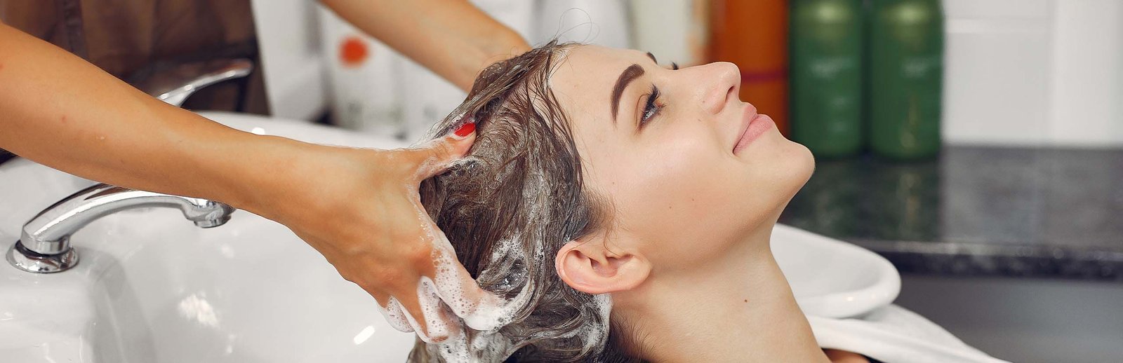 Hairdresser washing head her client. Woman in a hair salon